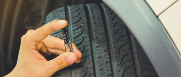 Main en train de mesurer l'usure d'un pneu voiture